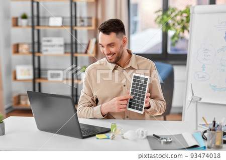 male teacher with laptop and solar battery at home 93474018