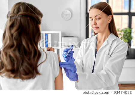female doctor with syringe vaccinating patient female doctor with syringe vaccinating patient 93474058