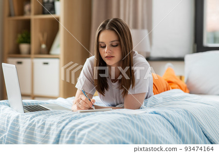 teenage student girl writing to notebook at home 93474164
