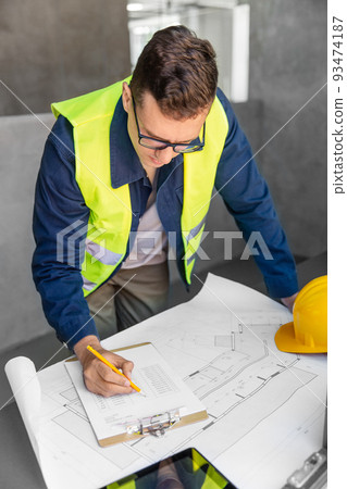 architect with blueprint and clipboard at office 93474187
