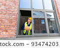 male builder with clipboard looking out window 93474203