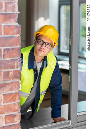 male builder in helmet looking out window male builder in helmet looking out window 93474211