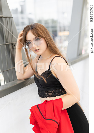 Stylish adorable pretty woman with long hair wearing black stylish suit and sunglasses standing and having fun in the street 93475703