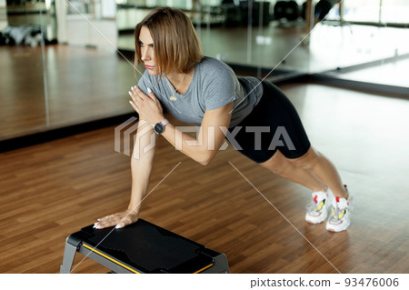 A sporty girl performs exercises using a bench. Photo of a sporty woman with a perfect body. Strength and motivation. Side view A sporty girl performs exercises using a bench. Photo of a sporty woman with a perfect body. Strength and motivation. Side view 93476006