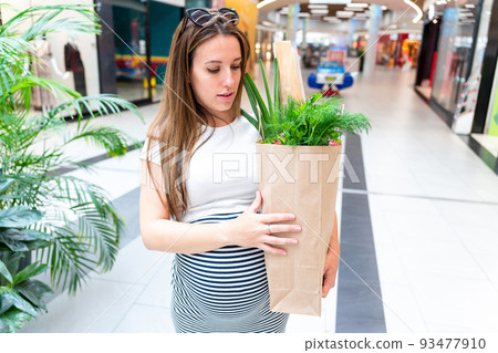 Pregnant healthy food bag. Pregnancy woman with healthy vegetables fresh, lettuce salad leaves in market food bag on grocery supermarket background. Healthy food background. Pregnant healthy food bag. Pregnancy woman with healthy vegetables fresh, lettuce salad leaves in market food bag on grocery supermarket background. Healthy food background. 93477910