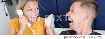 Joyful woman and man calling by phone from hotel room 93478295