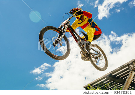 cyclist drops downhill in bokeh background blue sky 93478391