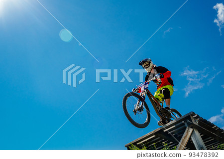 rider drops downhill in background blue sky 93478392