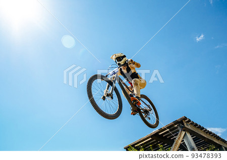 girl rider drops downhill in background blue sky 93478393
