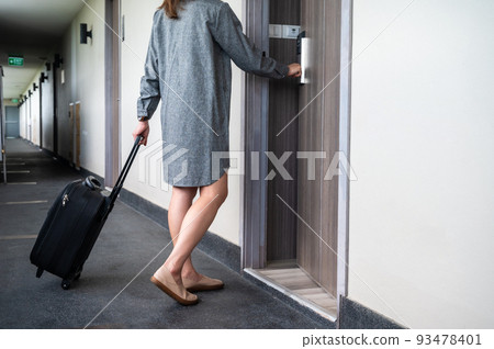Cropped shot view of tourist woman pulling her luggage to her hotel room after check-in. Conceptual of travel and vacation. Cropped shot view of tourist woman pulling her luggage to her hotel room after check-in. Conceptual of travel and vacation. 93478401