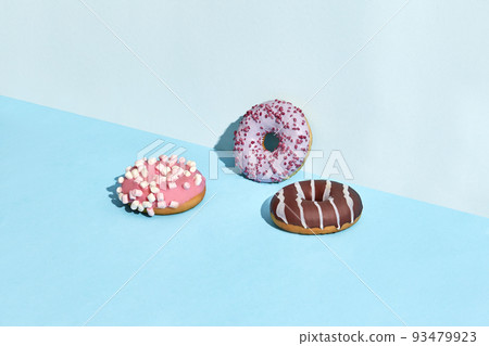 Three sweet tasty donuts in caramel and chocolate icing, on a two-color background Three sweet tasty donuts in caramel and chocolate icing, on a two-color background 93479923