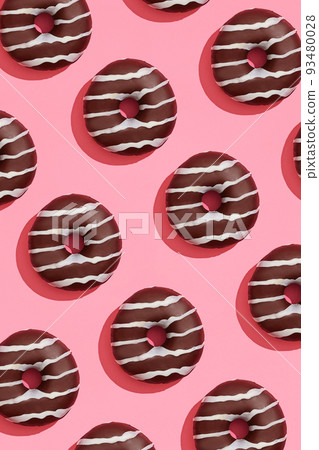 Food design with tasty chocolate glazed donut with white strips on coral pink pastel background top view pattern Food design with tasty chocolate glazed donut with white strips on coral pink pastel background top view pattern 93480028