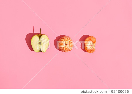 Food design. Composition of half of apple, peeled mandarin and half of peeled mandarin on pink coral background 93480056