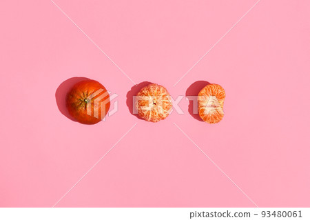 Food design. Composition of whole mandarin, peeled mandarin and half of peeled mandarin on pink coral background 93480061