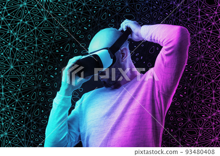 Young bald man put on VR glasses. Black background with neon abstract mesh. The concept of virtual reality, metaverse and cyberspace 93480408