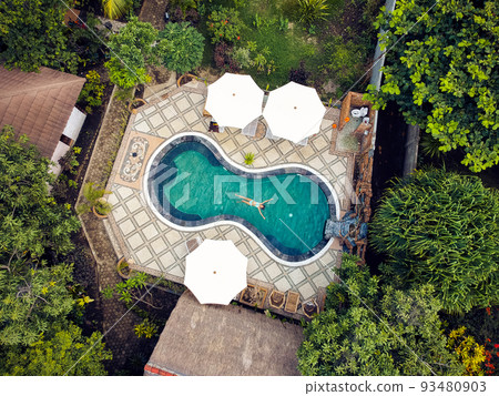 a young girl with pleasure swims in the pool.the view from the top a young girl with pleasure swims in the pool.the view from the top 93480903