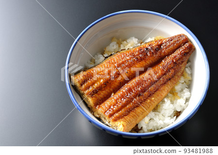 A simple eel bowl with eel kabayaki on top of white rice, taken from above with a black background 93481988