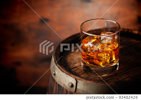 Glass of whiskey with ice cubes on the old barrel Glass of whiskey with ice cubes on the old barrel 93482428
