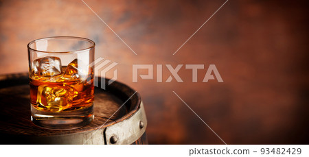 Glass of whiskey with ice cubes on the old barrel 93482429
