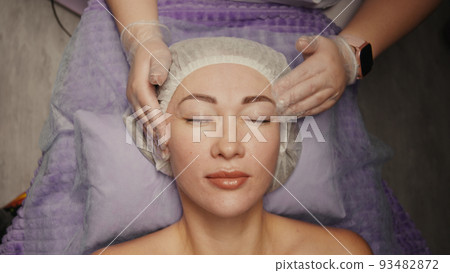 Woman receiving anti-ageing facial massage in spa salon relax. Wellness body skin care face beauty treatment. Black background Woman receiving anti-ageing facial massage in spa salon relax. Wellness body skin care face beauty treatment. Black background 93482872