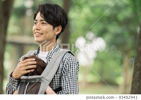 一個年輕的父親把他的孩子抱在背帶裡 一個年輕的父親把他的孩子抱在背帶裡 93482941