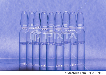 Glass medical ampoule vial for injection. Medicine is liquid sodium chloride with of aqueous solution in ampulla. Close up. Bottles ampule multicolor. Glass medical ampoule vial for injection. Medicine is liquid sodium chloride with of aqueous solution in ampulla. Close up. Bottles ampule multicolor. 93482948