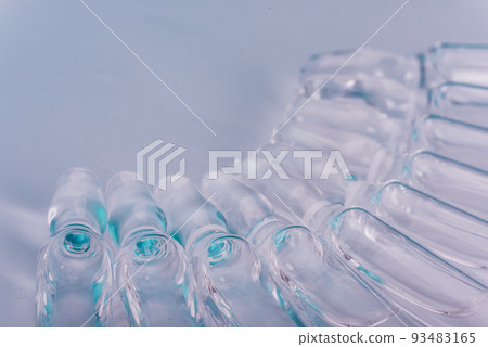 Glass medical ampoule vial for injection. Medicine is liquid sodium chloride with of aqueous solution in ampulla. Close up. Bottles ampule multicolor. Glass medical ampoule vial for injection. Medicine is liquid sodium chloride with of aqueous solution in ampulla. Close up. Bottles ampule multicolor. 93483165