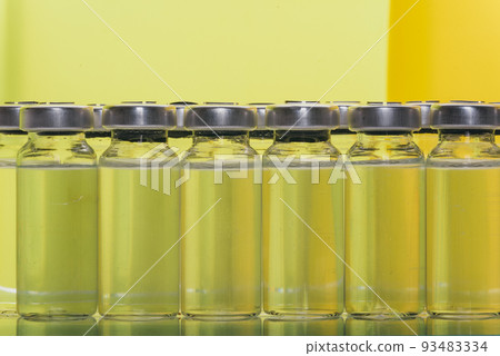 Glass medical ampoule vial for injection. Medicine is liquid sodium chloride with of aqueous solution in ampulla. Close up. Bottles ampule multicolor. Glass medical ampoule vial for injection. Medicine is liquid sodium chloride with of aqueous solution in ampulla. Close up. Bottles ampule multicolor. 93483334