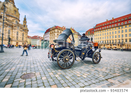 Old carriage on blurred background of Frauenkirche at Neumarkt square in downtown of Dresden. Old carriage on blurred background of Frauenkirche at Neumarkt square in downtown of Dresden. 93483574