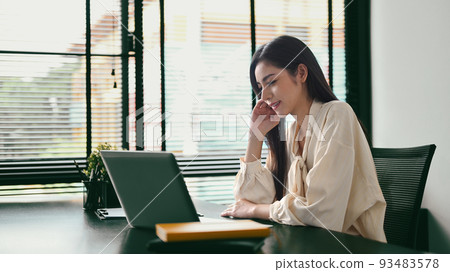 Gorgeous woman entrepreneur sitting in her contemporary office and checking information on laptop Gorgeous woman entrepreneur sitting in her contemporary office and checking information on laptop 93483578