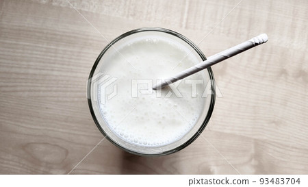 A glass of kefir on the table with a paper tube A glass of kefir on the table with a paper tube 93483704
