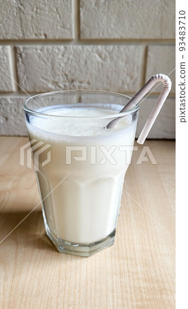A glass of kefir on the table with a paper tube 93483710