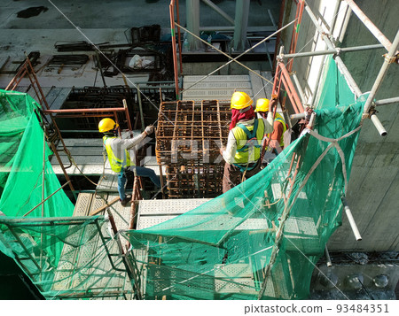 KLANG, MALAYSIA -MARCH 31, 2022: Construction workers fabricating steel reinforcement bar at the construction site. They tied it together using the tiny wires. It is part of reinforcement concrete. KLANG, MALAYSIA -MARCH 31, 2022: Construction workers fabricating steel reinforcement bar at the construction site. They tied it together using the tiny wires. It is part of reinforcement concrete. 93484351