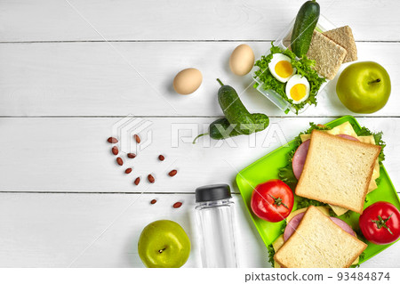 Lunch. Sandwich and fresh vegetables, bottle of water, nuts and fruits on white wooden background. Healthy eating concept. Top view with copy space Lunch. Sandwich and fresh vegetables, bottle of water, nuts and fruits on white wooden background. Healthy eating concept. Top view with copy space 93484874