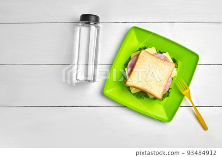 Cheese and ham sandwich, bottle of water on white wooden table. Healthy lunch idea concept Cheese and ham sandwich, bottle of water on white wooden table. Healthy lunch idea concept 93484912