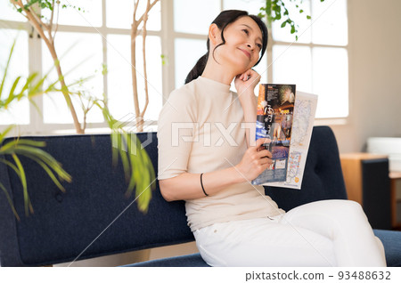 Middle woman thinking while looking at a pamphlet Middle woman thinking while looking at a pamphlet 93488632