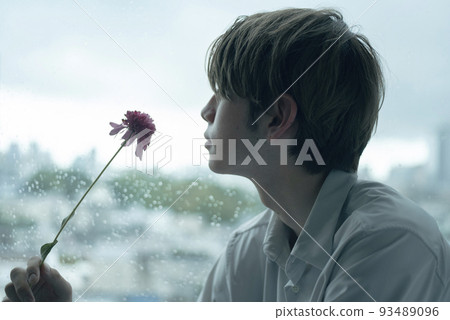 A man relaxing by the window on a rainy day A man relaxing by the window on a rainy day 93489096