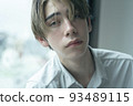 A man relaxing by the window on a rainy day 93489115