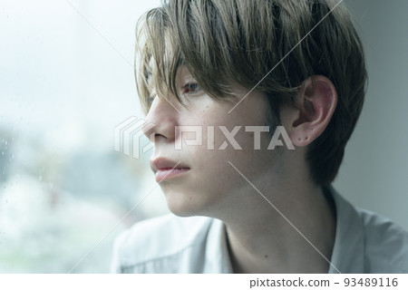 A man relaxing by the window on a rainy day 93489116