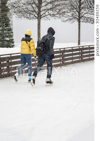 Young couple skating outdoors at the rink in winter park 93489359
