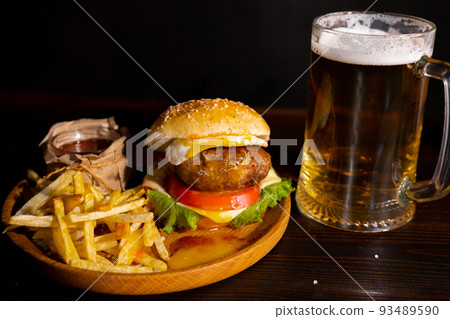 Set of hamburger beer and french fries. A standard set of drinks and food in the pub, beer and snacks. Dark background, fast food. Traditional american food. 93489590