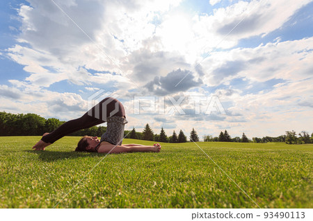 Woman stretching on green grass before yoga or fitness in park Woman stretching on green grass before yoga or fitness in park 93490113