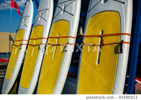 Yellow and white surfboards stand on the beach. 93490821