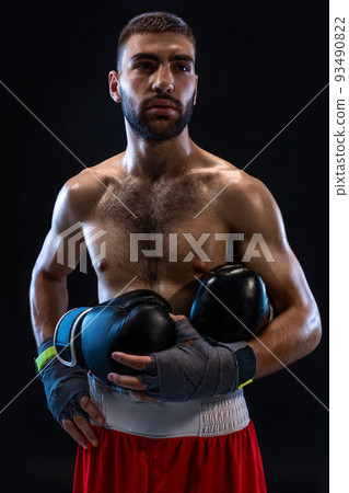 Man's hands in boxing bandages holds boxing gloves on a black background. Man's hands in boxing bandages holds boxing gloves on a black background. 93490822