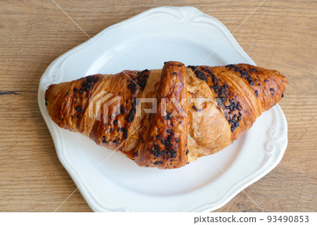 Delicious chocolodic croissant on a white plate in a cafe. Light and delicious breakfast. Delicious chocolodic croissant on a white plate in a cafe. Light and delicious breakfast. 93490853