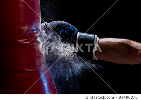 Close-up hand of boxer at the moment of impact on punching bag over black background 93490876