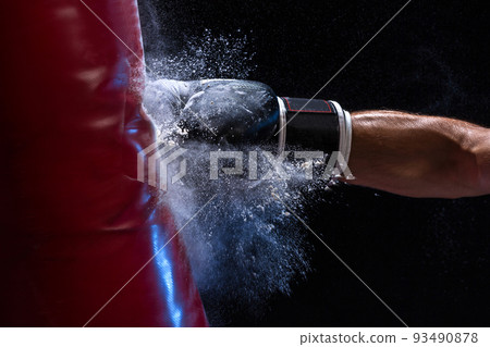 Close-up hand of boxer at the moment of impact on punching bag over black background 93490878