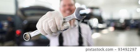 Male repairman holding wrench in car workshop closeup 93492297
