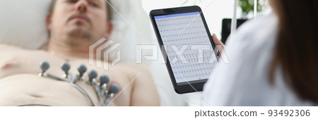 Doctor taking cardiogram to patient on couch in clinic closeup 93492306