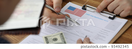 Man filling out paperwork for american visa with help of consultant closeup 93492345